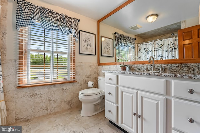 665 Bayard Rd, Lothian, MD 20711 - bathroom featuring tile walls, vanity, healthy amount of natural light, toilet, and wainscoting