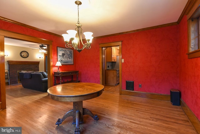 67 N American St, Woodbury, NJ 08096 - dining room featuring wood finished floors, a brick fireplace, a ceiling fan, a chandelier, and ornamental molding