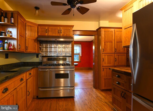 67 N American St, Woodbury, NJ 08096 - kitchen featuring stainless steel appliances, under cabinet range hood, dark countertops, wood finished floors, and brown cabinets