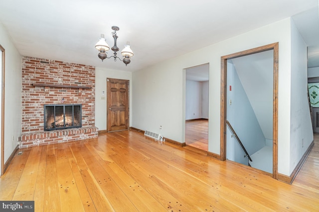 56 Pine Dr, Kirkwood, PA 17536 - unfurnished living room featuring a chandelier, hardwood / wood-style flooring, a brick fireplace, and baseboards