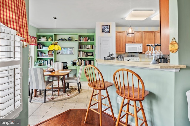 8145 Cyprus Cedar Ln Unit C, Ellicott City, MD 21043 - kitchen with white microwave, stove, light tile patterned flooring, pendant lighting, and a breakfast bar area