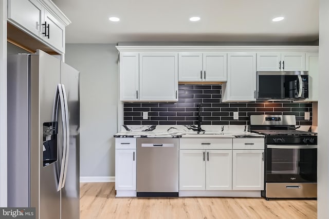 1235 Delbert, Baltimore, MD 21222 - kitchen with appliances with stainless steel finishes, a sink, light wood finished floors, white cabinets, and backsplash