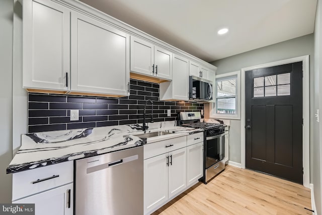 1235 Delbert, Baltimore, MD 21222 - kitchen featuring appliances with stainless steel finishes, light wood finished floors, backsplash, a sink, and white cabinetry