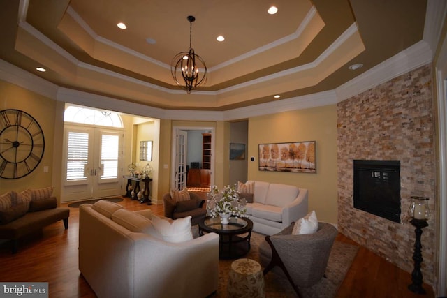 35517 Bonaire Dr, Rehoboth Beach, DE 19971 - living area with crown molding, a tray ceiling, a stone fireplace, wood finished floors, and a chandelier