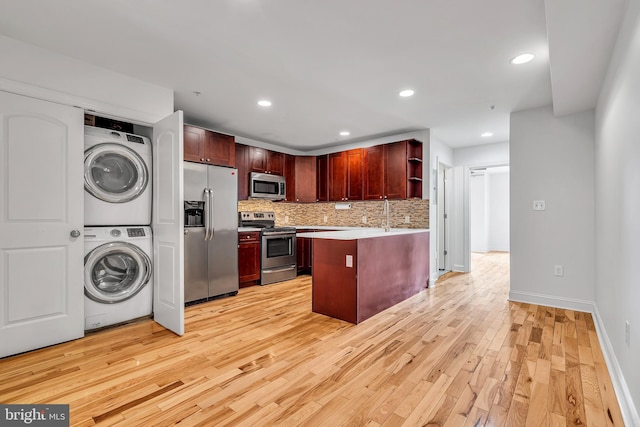 821 N 15th St Unit 2, Philadelphia, PA 19130 - kitchen with stainless steel appliances, stacked washing machine and dryer, open shelves, a peninsula, and light wood-style flooring