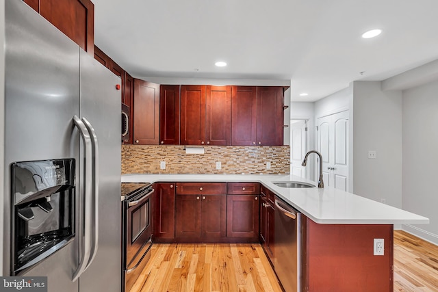 821 N 15th St Unit 2, Philadelphia, PA 19130 - kitchen featuring appliances with stainless steel finishes, a peninsula, dark brown cabinets, light wood-style floors, and recessed lighting