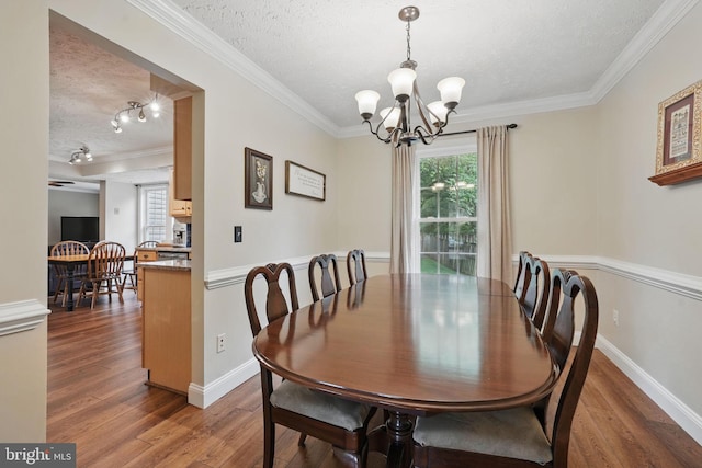 4549 Diehl Ct, Woodbridge, VA 22193 - dining space featuring a textured ceiling, ornamental molding, a chandelier, wood finished floors, and baseboards