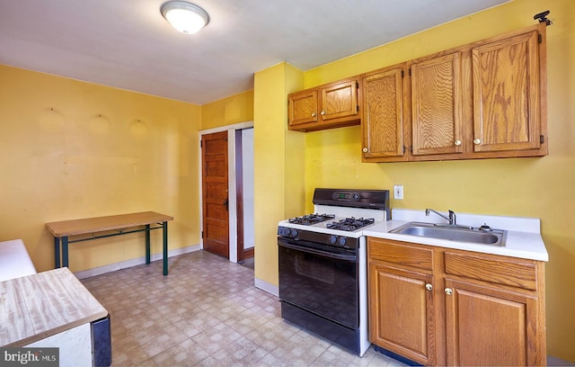 625 Hunter St, Gloucester City, NJ 08030 - kitchen with gas stove, a sink, light flooring, light countertops, and baseboards