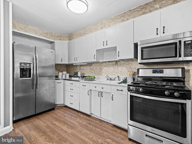 2521 Moore Ave, Baltimore, MD 21234 - kitchen with appliances with stainless steel finishes, a sink, light wood-style flooring, white cabinets, and light countertops