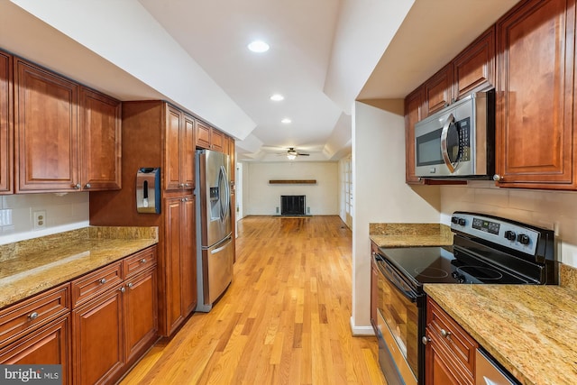 46 Misty Ln, Stafford, VA 22556 - kitchen featuring appliances with stainless steel finishes, a fireplace, light wood-style flooring, ceiling fan, and decorative backsplash