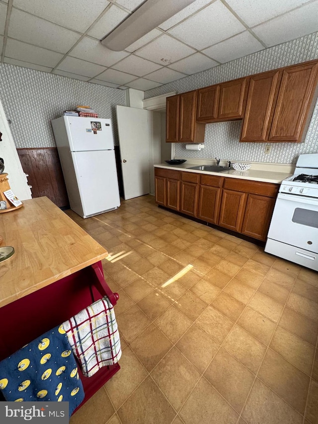 73 Fairfield Ave, Lawrence, NJ 08648 - kitchen featuring white appliances, wallpapered walls, a sink, a drop ceiling, and brown cabinets