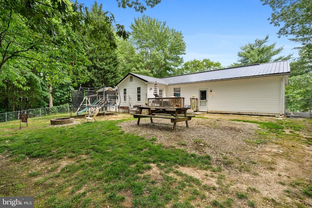 27073 Carrie Ct, Mechanicsville, MD 20659 - rear view of house featuring a wooden deck, a fire pit, metal roof, and a trampoline