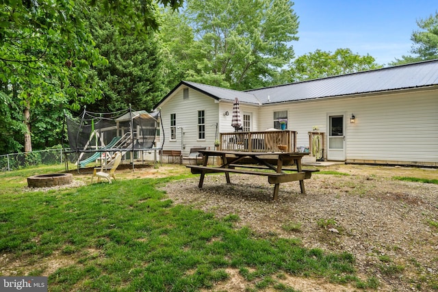 27073 Carrie Ct, Mechanicsville, MD 20659 - back of property featuring a trampoline, a fire pit, a wooden deck, and metal roof