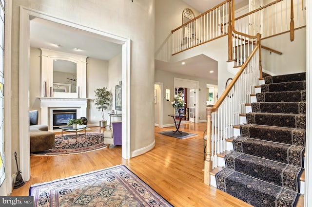 826 Bent Creek Dr, Lititz, PA 17543 - entryway featuring wood finished floors, stairway, a towering ceiling, baseboards, and a glass covered fireplace