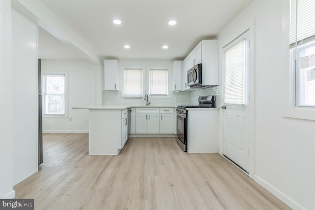 395 Main St, Cedarville, NJ 08311 - kitchen with stainless steel appliances, light wood-type flooring, white cabinets, backsplash, and baseboards