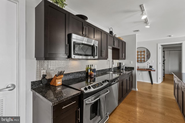 1200 Steuart St Unit 326, Baltimore, MD 21230 - kitchen with appliances with stainless steel finishes, a sink, backsplash, dark stone countertops, and light wood finished floors