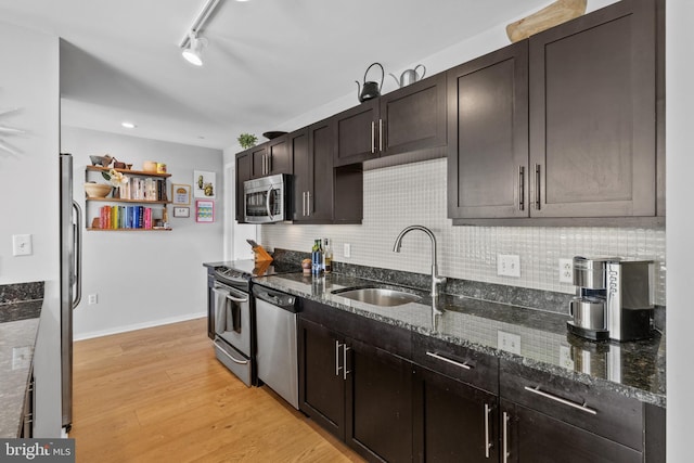1200 Steuart St Unit 326, Baltimore, MD 21230 - kitchen featuring stainless steel appliances, a sink, dark stone counters, light wood-style flooring, and decorative backsplash
