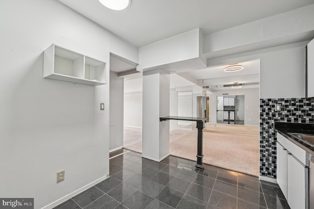 3601 Clarks Ln Unit 424, Baltimore, MD 21215 - kitchen featuring granite floors, dark countertops, white cabinets, baseboards, and a sink