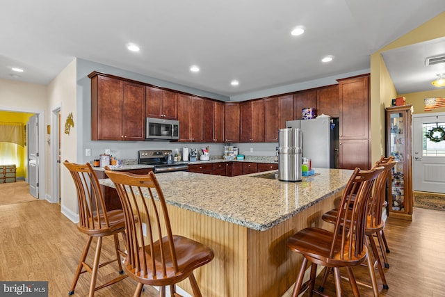 20843 Country Rd, Georgetown, DE 19947 - kitchen with stainless steel appliances, light wood-style floors, light stone countertops, a kitchen breakfast bar, and recessed lighting