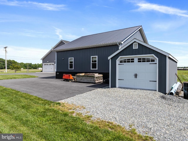 20843 Country Rd, Georgetown, DE 19947 - view of side of home featuring an outdoor structure, board and batten siding, metal roof, a lawn, and driveway
