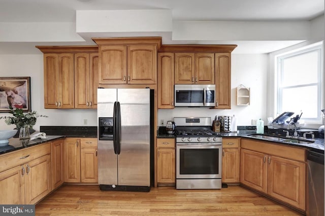 1316 Irving St NW, Washington, DC 20010 - kitchen with appliances with stainless steel finishes, a sink, light wood-style floors, and brown cabinetry