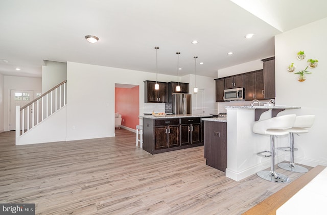 6320 Neha Dr, Mechanicsburg, PA 17050 - kitchen featuring appliances with stainless steel finishes, light wood-style flooring, dark brown cabinetry, a kitchen bar, and recessed lighting
