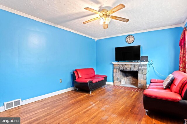 201 Village Rd, Harrisburg, PA 17112 - living area with a textured ceiling, ceiling fan, wood-type flooring, baseboards, and a stone fireplace