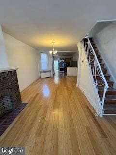 2012 E Glenwood Ave, Philadelphia, PA 19124 - unfurnished living room featuring wood finished floors, a fireplace, stairs, and a chandelier