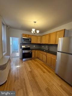 2012 E Glenwood Ave, Philadelphia, PA 19124 - kitchen with stainless steel appliances, a chandelier, light wood-style flooring, dark countertops, and decorative light fixtures
