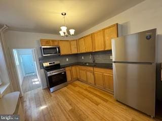 2012 E Glenwood Ave, Philadelphia, PA 19124 - kitchen with appliances with stainless steel finishes, a chandelier, light wood-style flooring, and tasteful backsplash