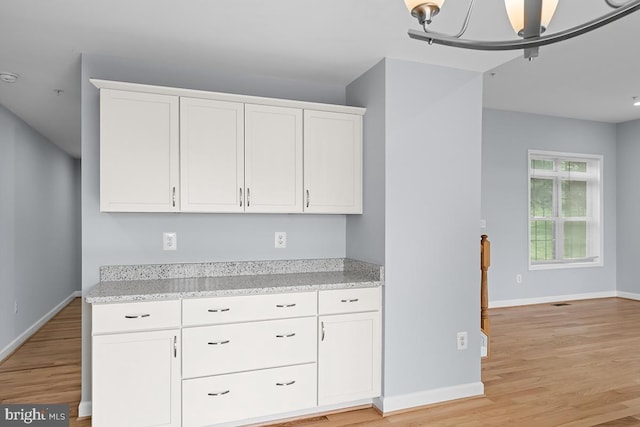 6712 Ridgecrest Rd, New Market, MD 21774 - kitchen with baseboards, light wood-style flooring, white cabinetry, and light stone counters