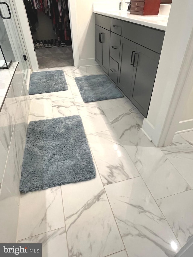 16801 Chalet Ct, Chesterfield, VA 23832 - bathroom featuring marble look tile flooring, a spacious closet, vanity, baseboards, and a shower with door