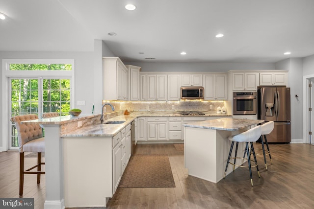 2 Jessica Ct, Tabernacle, NJ 08088 - kitchen featuring appliances with stainless steel finishes, a sink, a breakfast bar, tasteful backsplash, and wood finished floors