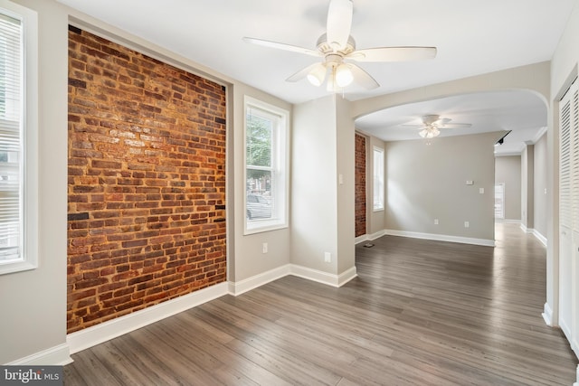 2808 Orleans St, Baltimore, MD 21224 - spare room with ceiling fan, arched walkways, wood finished floors, baseboards, and brick wall