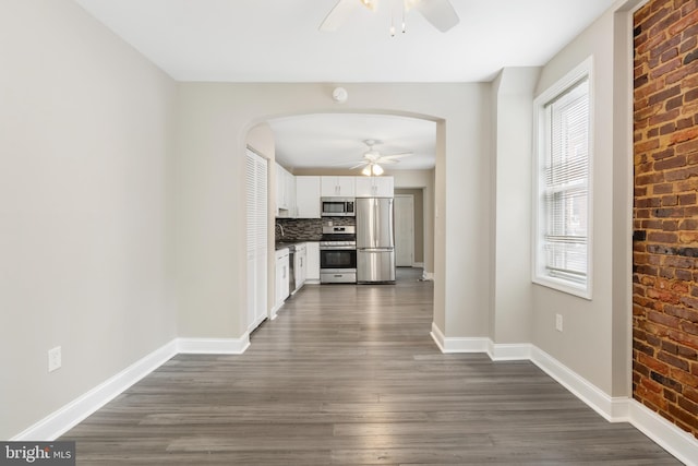 2808 Orleans St, Baltimore, MD 21224 - kitchen featuring stainless steel appliances, ceiling fan, arched walkways, white cabinetry, and dark wood finished floors