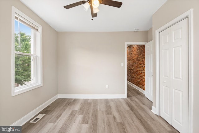 2808 Orleans St, Baltimore, MD 21224 - unfurnished bedroom with brick wall, light wood finished floors, baseboards, a ceiling fan, and a closet