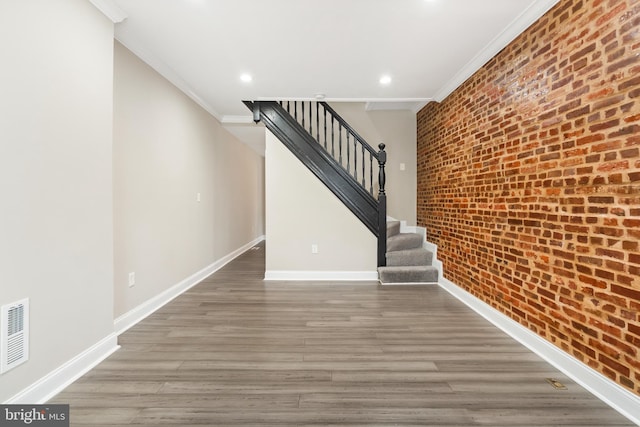 2808 Orleans St, Baltimore, MD 21224 - stairs with ornamental molding, brick wall, wood finished floors, baseboards, and recessed lighting