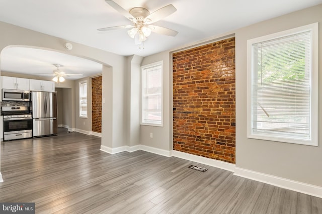 2808 Orleans St, Baltimore, MD 21224 - unfurnished living room featuring a ceiling fan, arched walkways, dark wood-style flooring, baseboards, and healthy amount of natural light