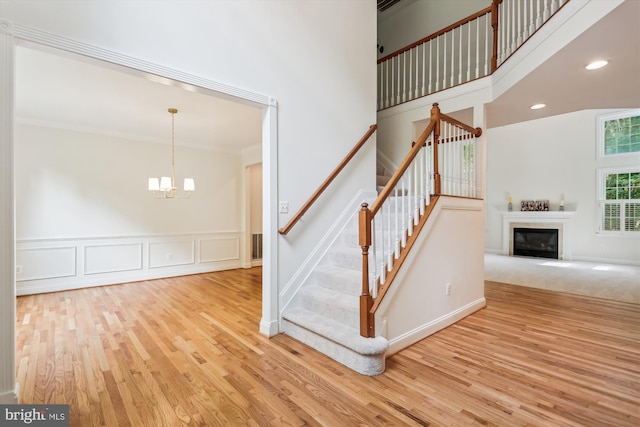 14908 Little Bennett Dr, Clarksburg, MD 20871 - stairs featuring wood finished floors, a chandelier, a glass covered fireplace, a wainscoted wall, and ornamental molding