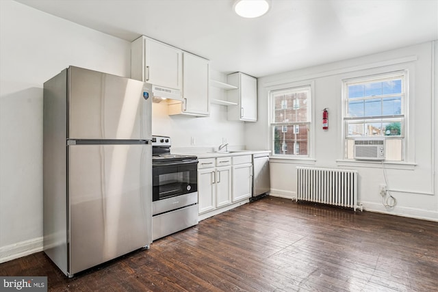 2425 E St NE, Washington, DC 20002 - kitchen featuring appliances with stainless steel finishes, radiator heating unit, under cabinet range hood, dark wood-style floors, and white cabinets