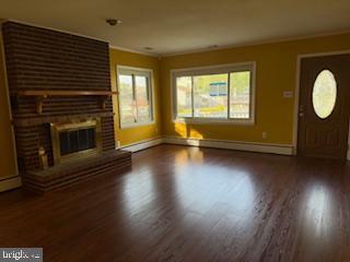 7686 Briar Ln, Pasadena, MD 21122 - unfurnished living room featuring wood finished floors, baseboards, a fireplace, and baseboard heating