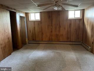 7686 Briar Ln, Pasadena, MD 21122 - basement featuring healthy amount of natural light, wooden walls, a drop ceiling, carpet, and baseboard heating