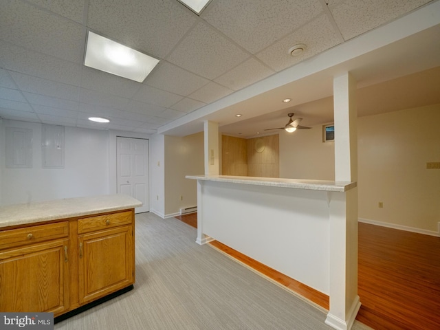 9407 7th St N, Laurel, MD 20723 - kitchen with brown cabinetry, light countertops, a drop ceiling, a ceiling fan, and a baseboard radiator