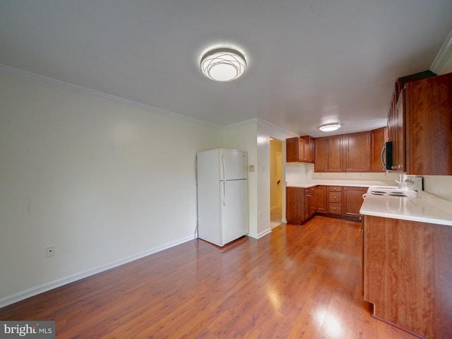 9407 7th St N, Laurel, MD 20723 - kitchen featuring freestanding refrigerator, stainless steel microwave, brown cabinets, crown molding, and wood finished floors