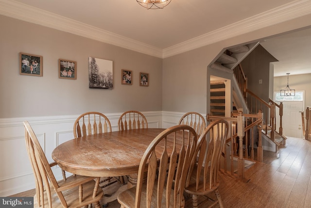 21008 Strawrick Ter, Ashburn, VA 20147 - dining room featuring stairway, wainscoting, wood finished floors, a decorative wall, and ornamental molding
