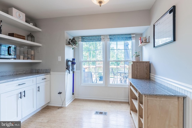 21008 Strawrick Ter, Ashburn, VA 20147 - kitchen featuring open shelves, a wainscoted wall, light wood finished floors, stainless steel microwave, and light stone countertops