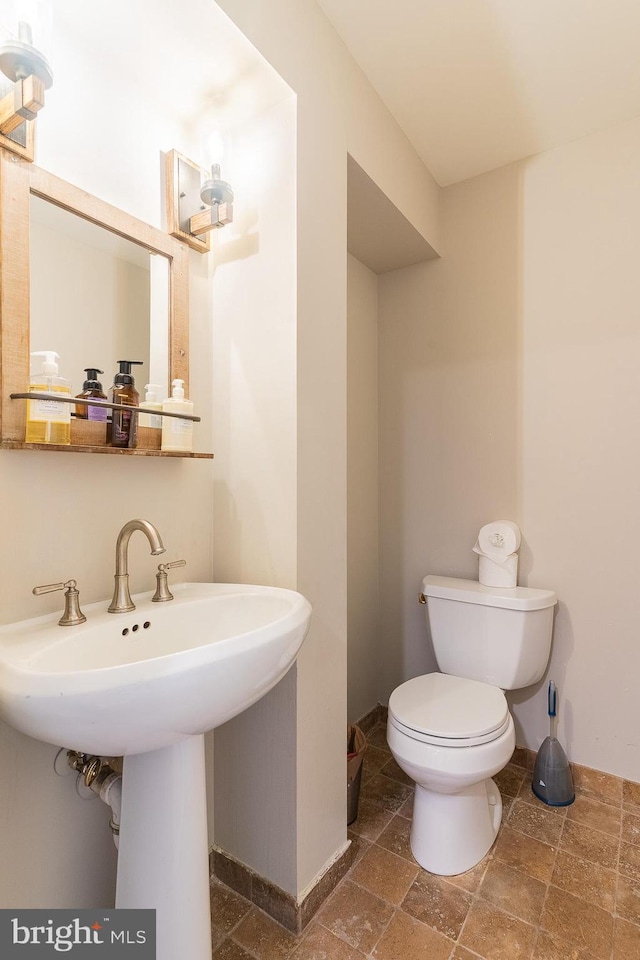 21008 Strawrick Ter, Ashburn, VA 20147 - half bathroom with toilet, baseboards, a sink, and stone finish floors
