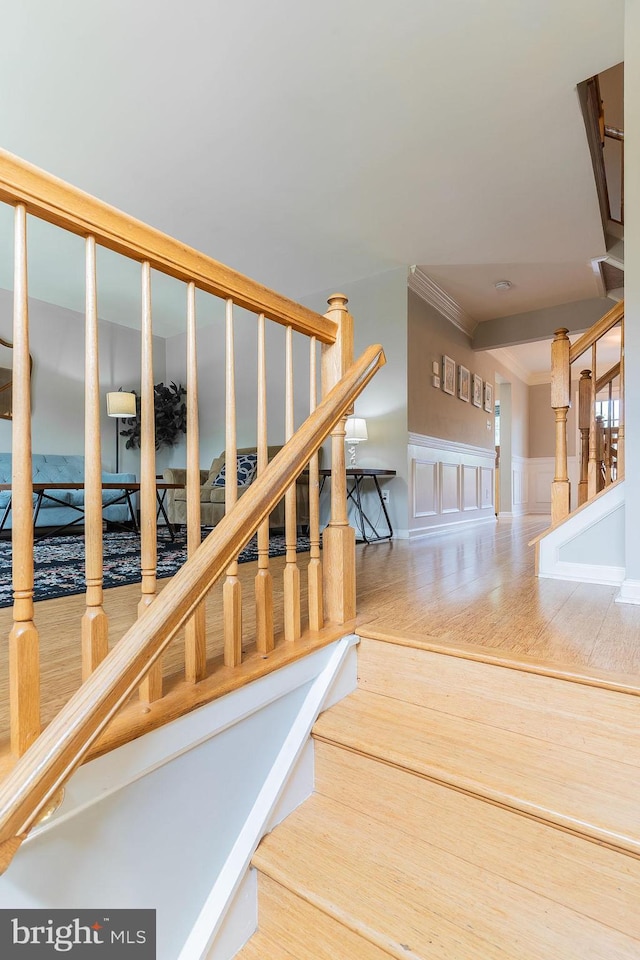 21008 Strawrick Ter, Ashburn, VA 20147 - staircase with wainscoting, crown molding, wood finished floors, and a decorative wall