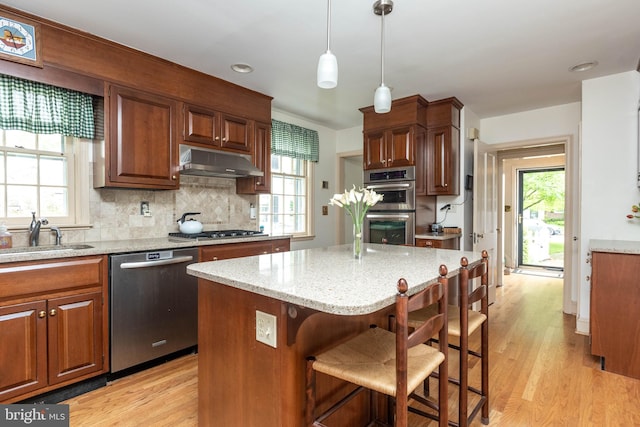 114 Bellemore Rd, Baltimore, MD 21210 - kitchen featuring stainless steel appliances, a sink, under cabinet range hood, light wood-style floors, and backsplash