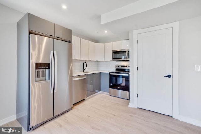 2639 Cecil B Moore Ave, Philadelphia, PA 19121 - kitchen with stainless steel appliances, light wood-style flooring, a sink, light countertops, and tasteful backsplash